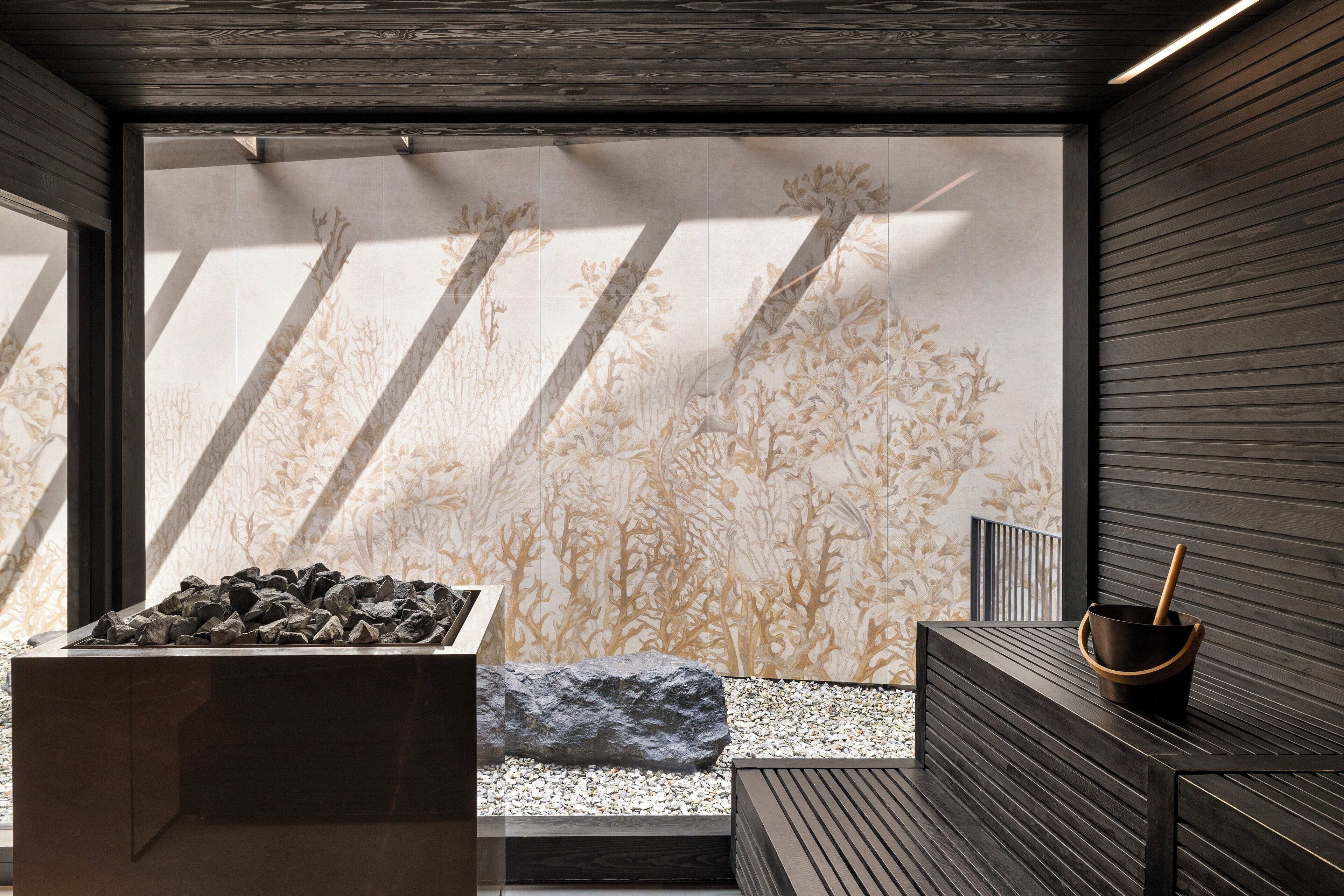 Ein modernes Interieur mit einem Felsengarten, einer Holzbank und einer Wand mit einem naturinspirierten Muster.