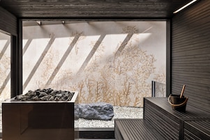 Un interior moderno con un jardín de rocas, un banco de madera y una pared con un diseño inspirado en la naturaleza.