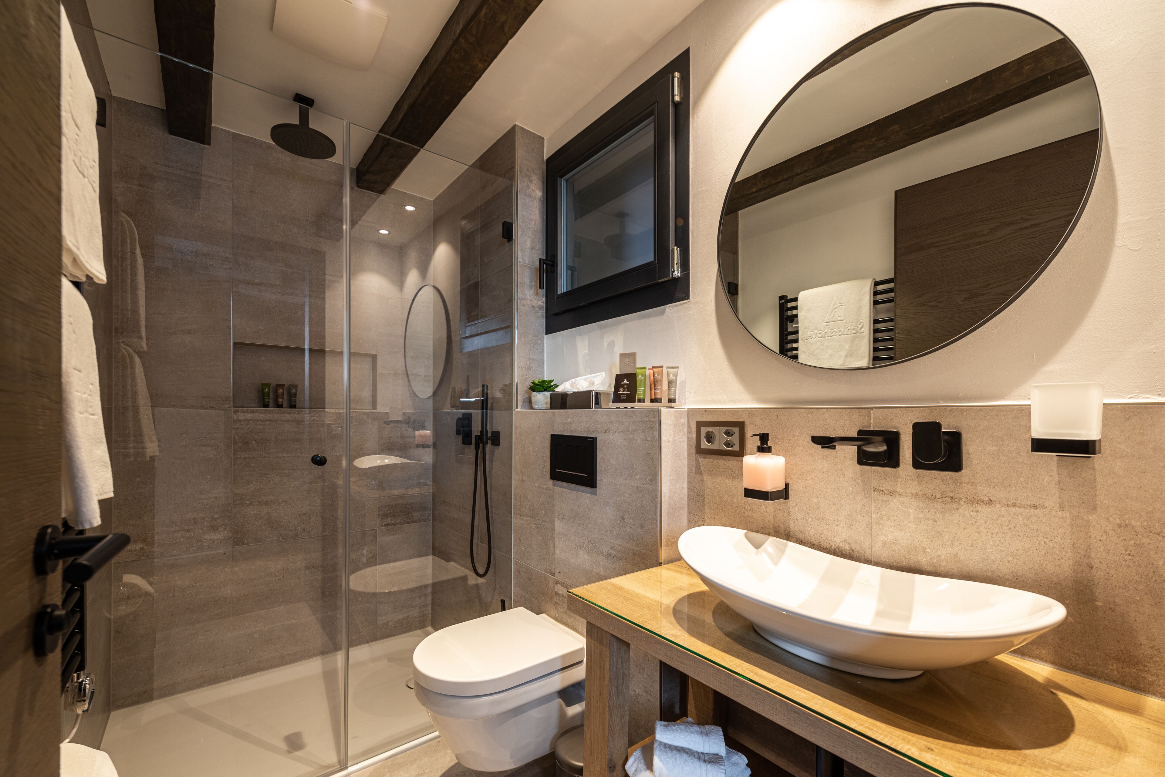 Un bagno moderno con doccia vetrata, un water bianco e un ampio lavabo ovale.