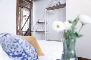 A bedroom with a bed, a bedside table, a nightstand, a wardrobe, and a mirror.
