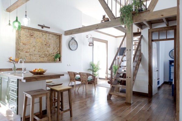 A spacious kitchen with a wooden island, bar stools, and a rustic stone wall.