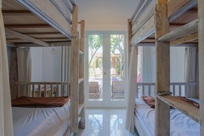 A corridor with bunk beds, a door leading outside, and a view of the outside area. - Art Canggu Village (Canggu)