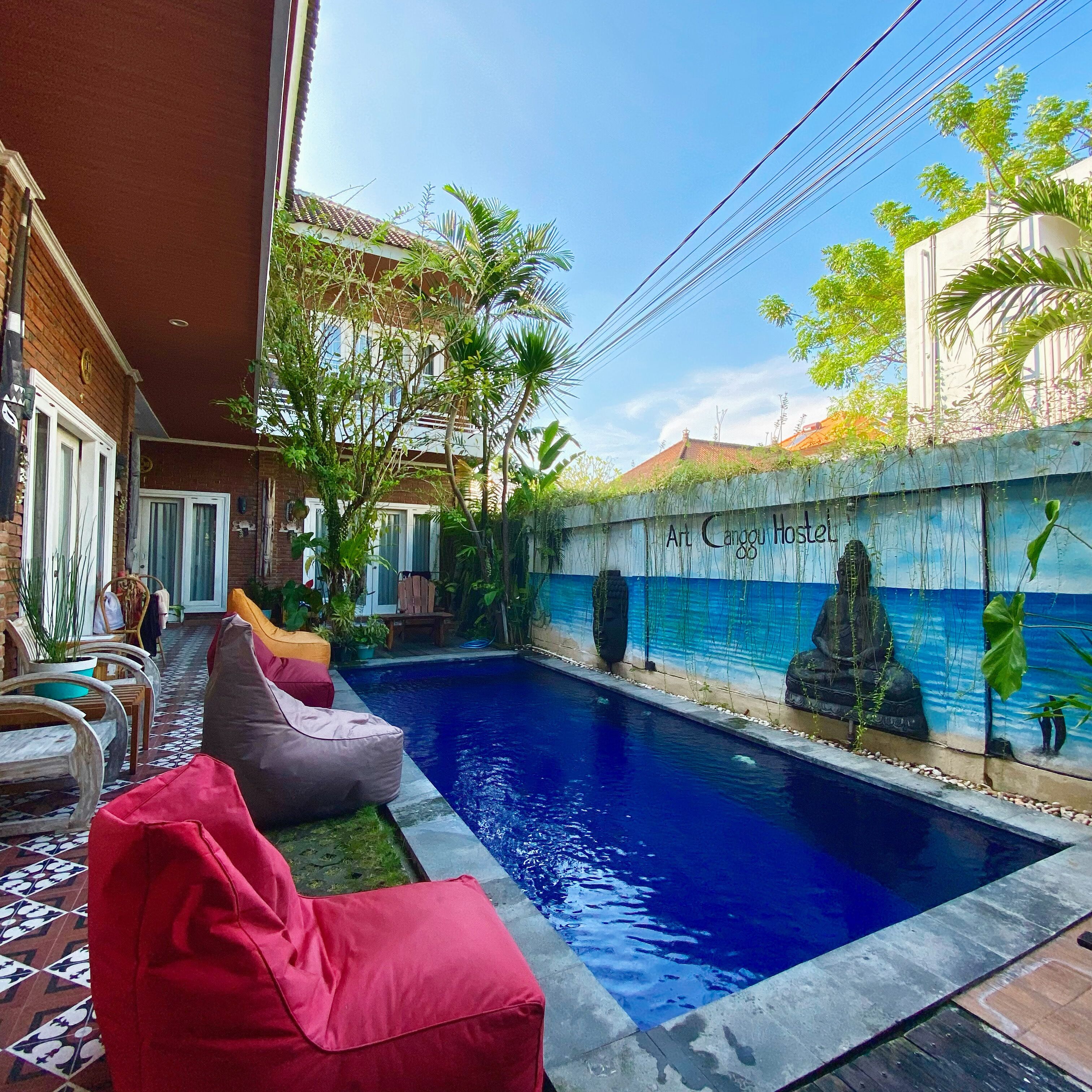 A swimming pool with a mural, outdoor seating, and a brick wall.
