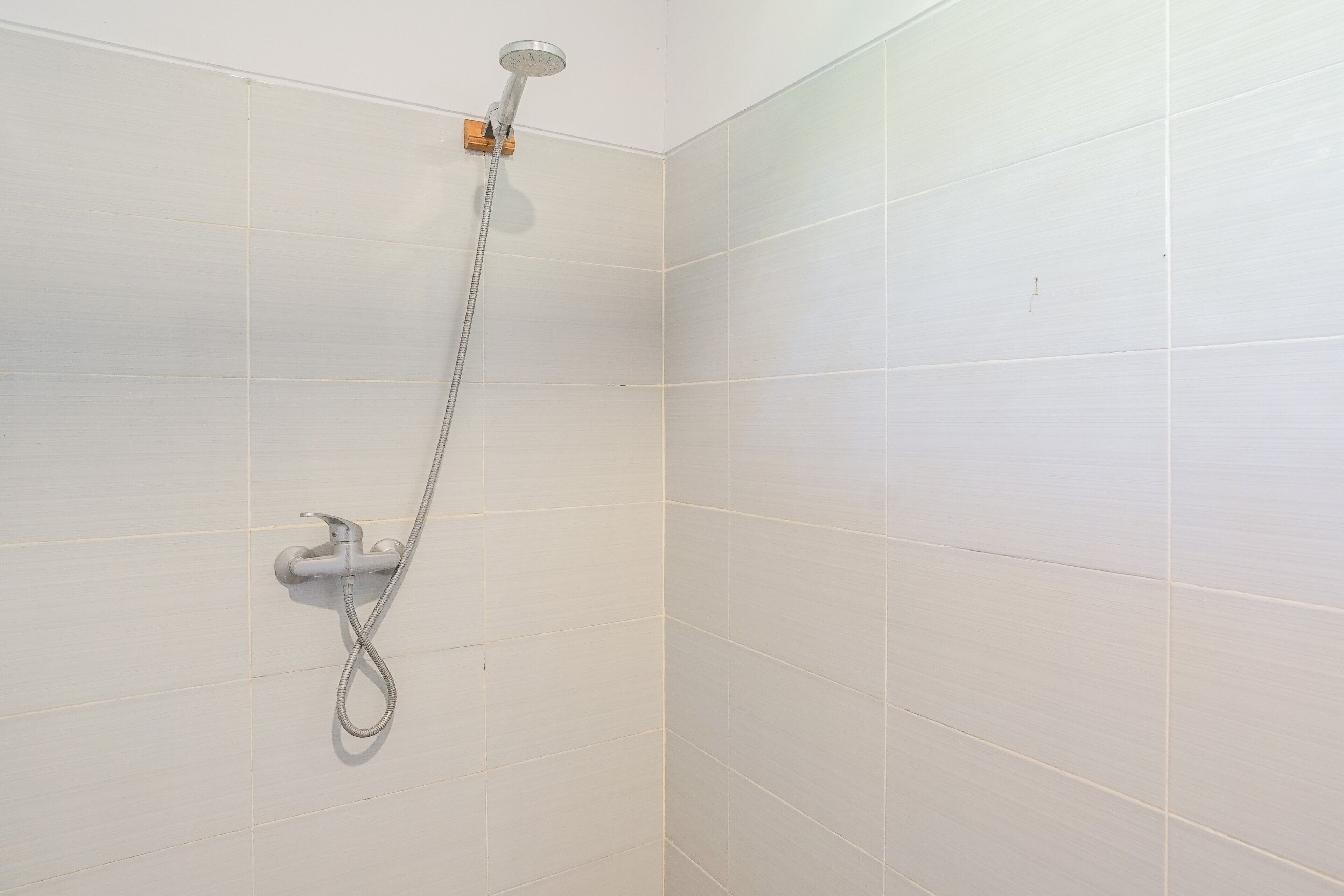 Brusebad med håndholdt brusehose og fastmonteret brusearmatur.