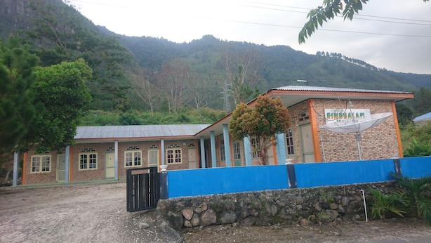 A two-story building with a brick facade and a blue roof. There is a sign on the building that reads "FURNIZONAL RINCONALAM."