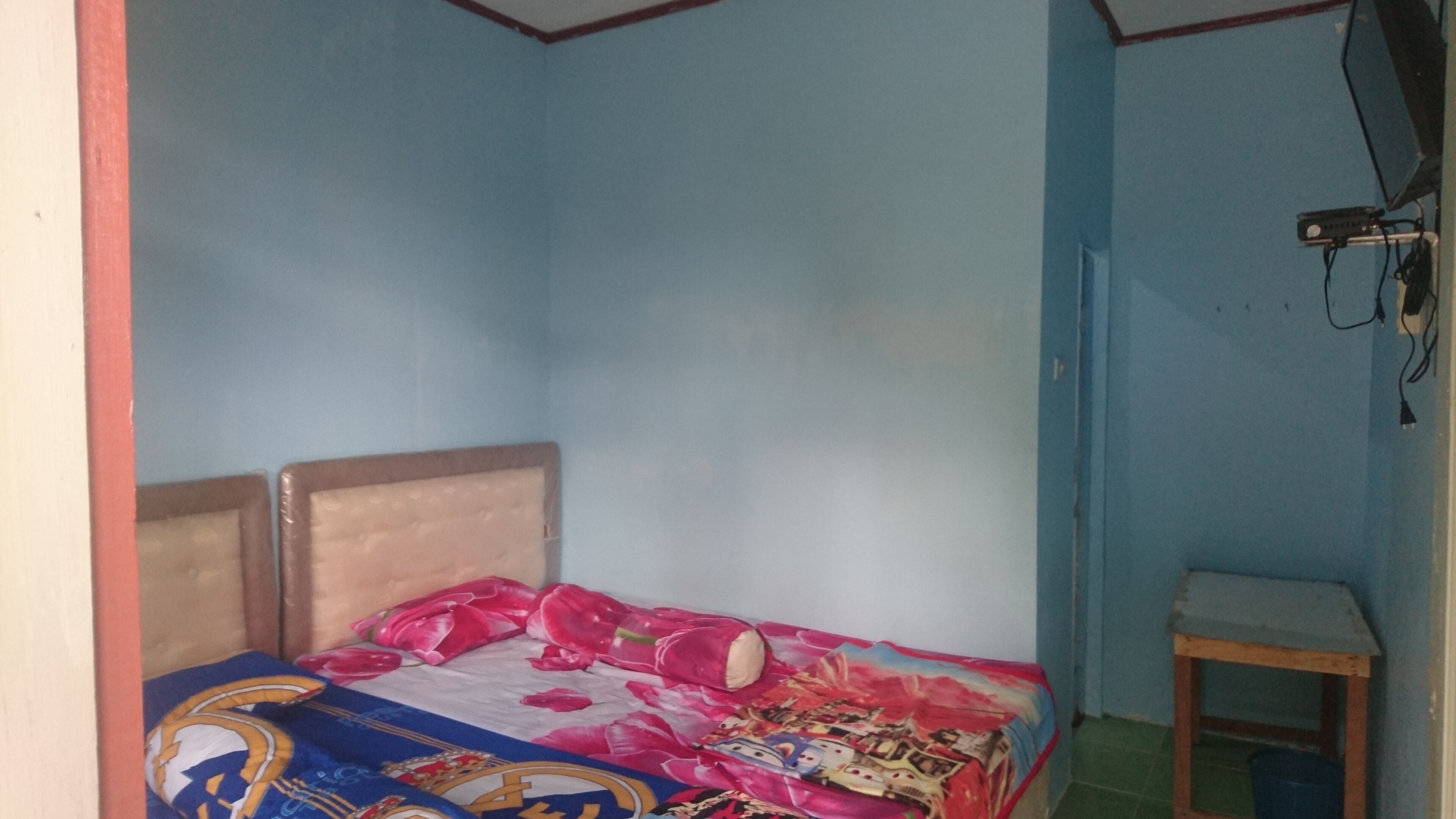 Un dormitorio pequeño con cama, mesita de noche y estante en la pared.