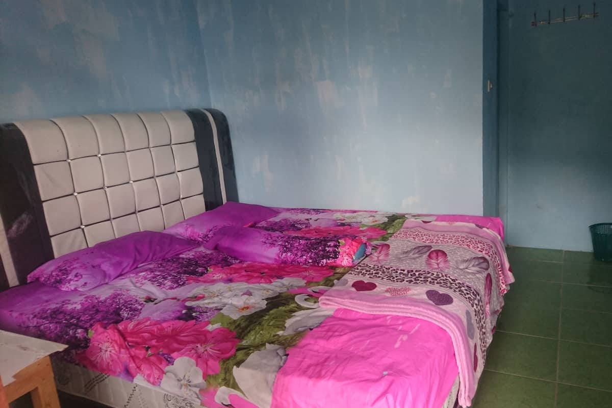 Un lit avec une couvre-lit à motifs floraux, une tête de lit et un sol vert.