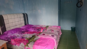 A bed with a floral bedspread, a headboard, and a green floor.