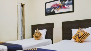 A hotel room with two single beds, each with a white pillow and a patterned pillow. There is a framed abstract painting on the wall above the beds. - SPOT ON 2375 Faris Homestay (Makassar)
