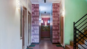 A hallway with a tiled floor, a staircase on the right, and a door on the left. - SPOT ON 2375 Faris Homestay (Makassar)