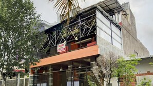 A building with a metal framework, a balcony, and a sign indicating a business. - SPOT ON 2375 Faris Homestay (Makassar)