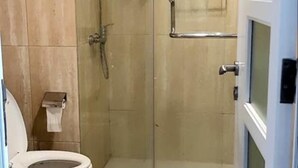 Un baño moderno con ducha de vidrio, inodoro y perchero para toallas.