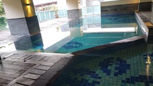 Una piscina interior con suelo de baldosas y vista despejada al área de la piscina.