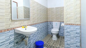 A bathroom with a white sink, a toilet, and a mirror. The walls are tiled with a patterned design. - Kompyang Rai Guest House (Canggu)