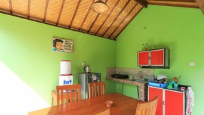 A kitchen with a wooden table and chairs, a refrigerator, a sink, and a cabinet. - Kompyang Rai Guest House (Canggu)