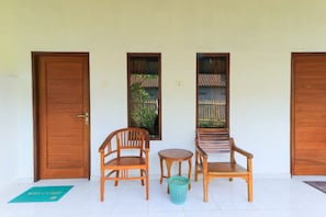 A room with two wooden doors, a small round table, two wooden chairs, and a green mat with "WELCOME" on it.