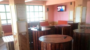 A restaurant interior with wooden tables and chairs, a whiteboard with writing, and a television on the wall. - Escarpment Motel - Adults Only (Mai Mahiu)