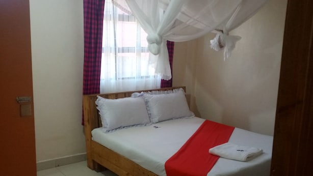 A single-bed room with a wooden frame, white bedding, and a red accent. - Escarpment Motel - Adults Only (Mai Mahiu)