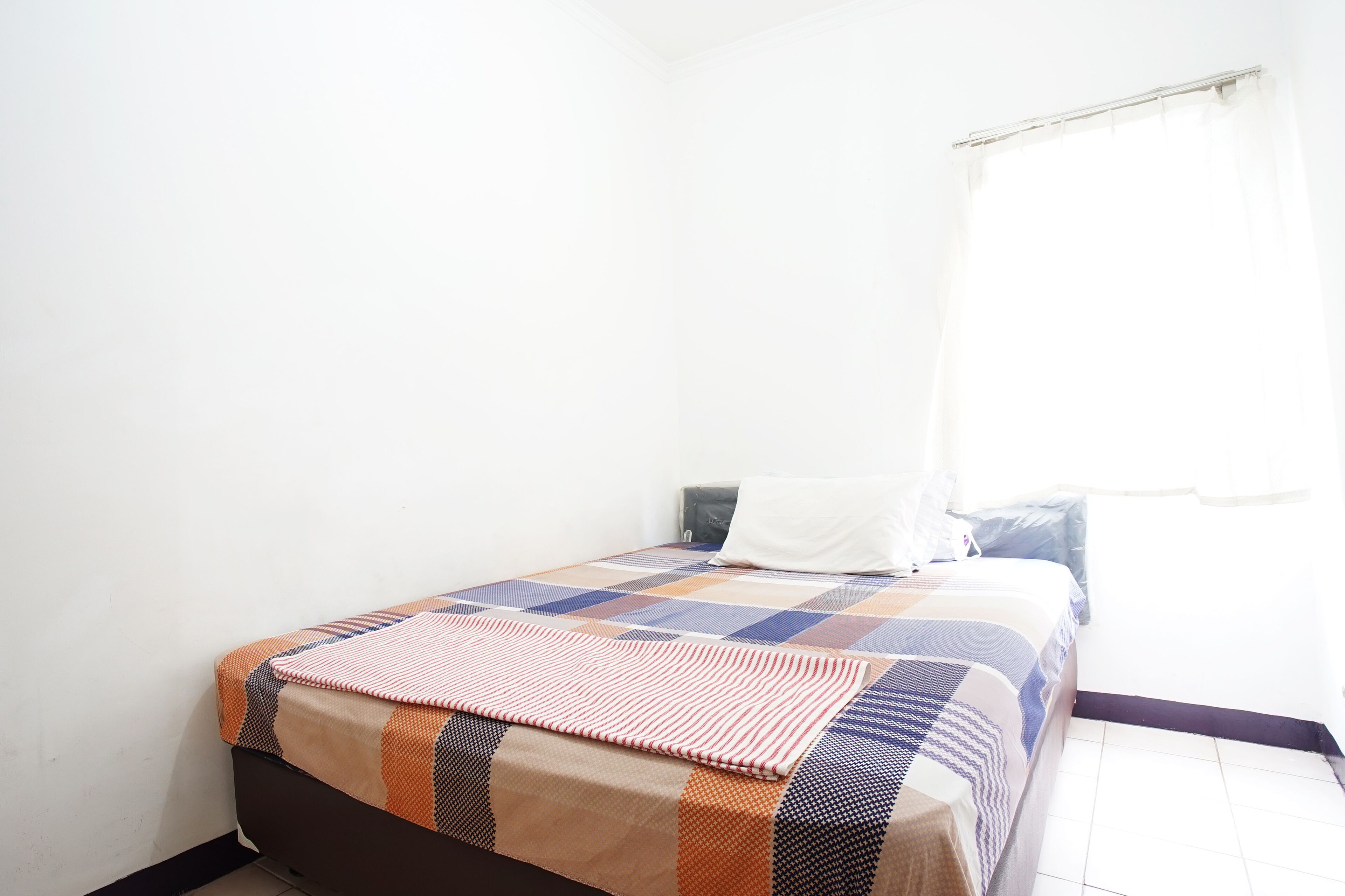 Un letto singolo con una coperta a motivi, un cuscino e un comodino con una lampada.