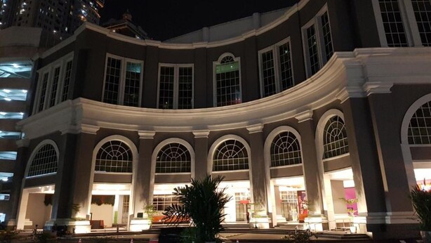 A large, multi-story building with a curved facade, large arched windows, and a central entrance.