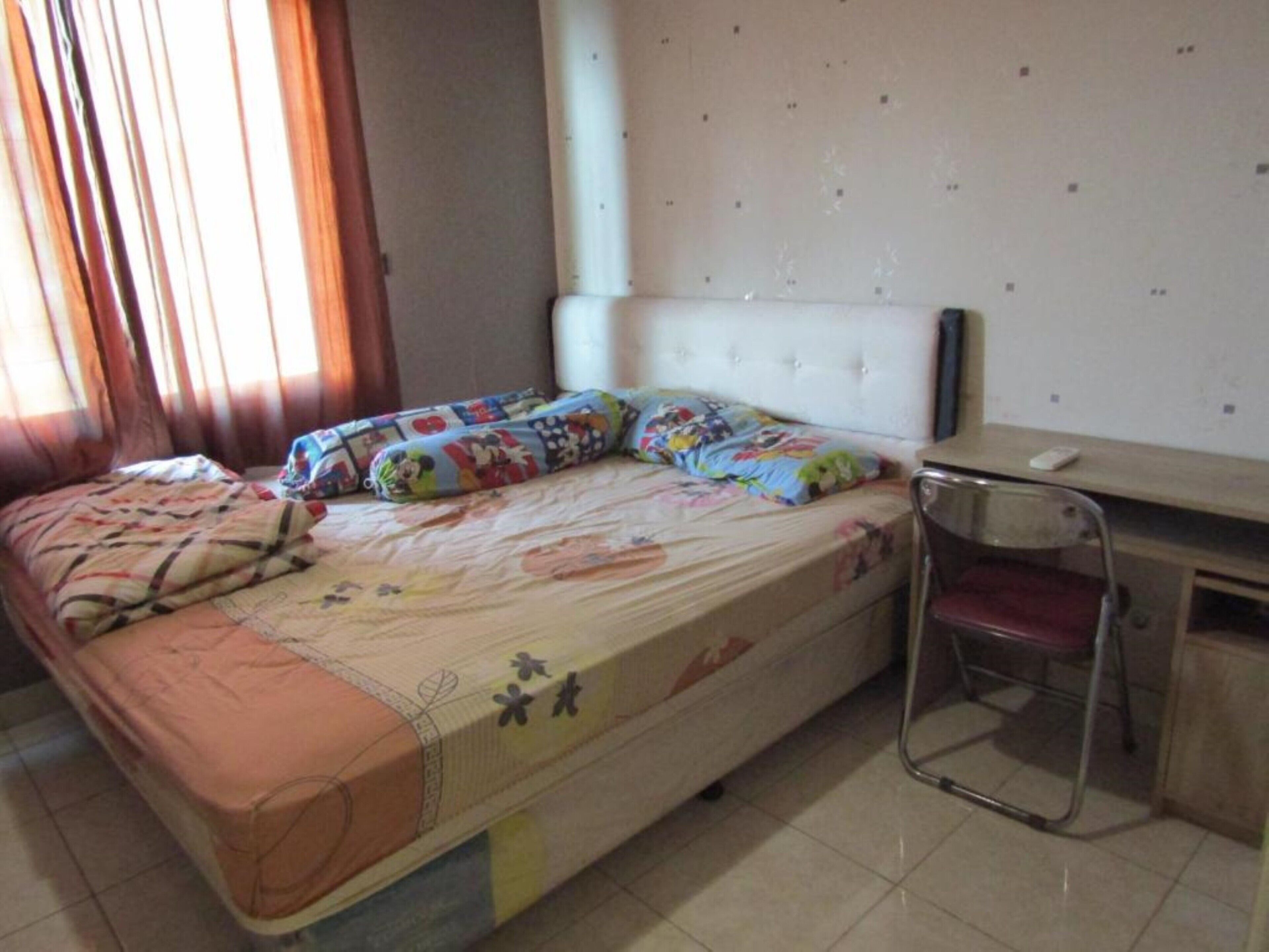 A bedroom with a bed, a desk, and a chair.