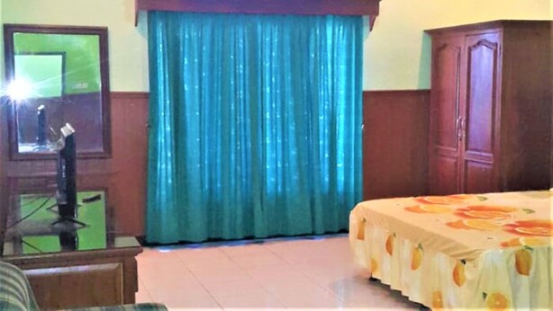 A hotel room with a bed, a clock, a mirror, and a window with curtains. - Hotel Mulia (Baki)