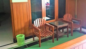 A room with wooden paneling, a glass table, two wooden chairs, and a green basket on the floor. - Hotel Mulia (Baki)