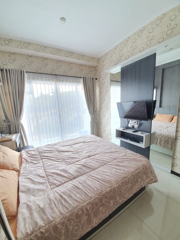 A modern bedroom with a large bed, a TV, and a wardrobe.