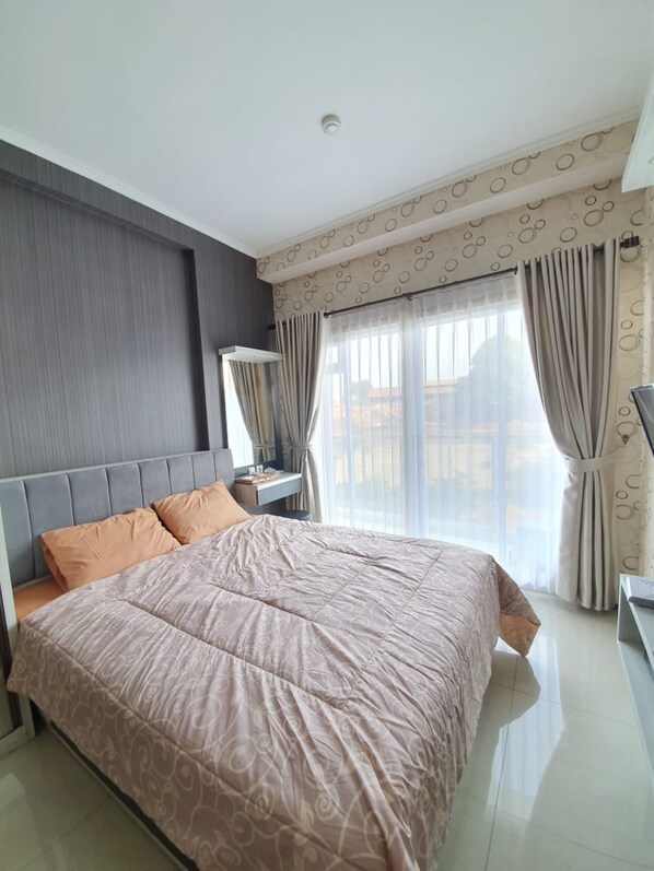 Un dormitorio moderno con una cama grande, una mesita de noche, un espejo y una ventana con cortinas.