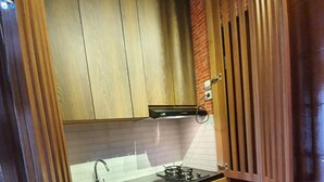 Een kleine keuken met houten kastjes, een gasfornuis en een spoelbak.