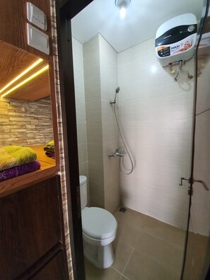 Un baño moderno con inodoro, ducha y dispensador de papel higiénico de pared.