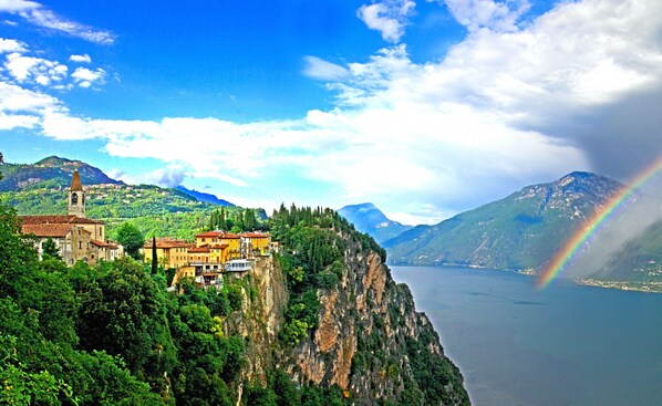 A coastal town with a prominent church, lush greenery, and a mountain backdrop.