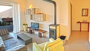 A modern living room with a sofa, a coffee table, a TV, and a fireplace. - Villetta sogno sul lago (Tremosine)