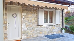 A stone facade with a door, a window with shutters, and a potted plant. - Villetta sogno sul lago (Tremosine)