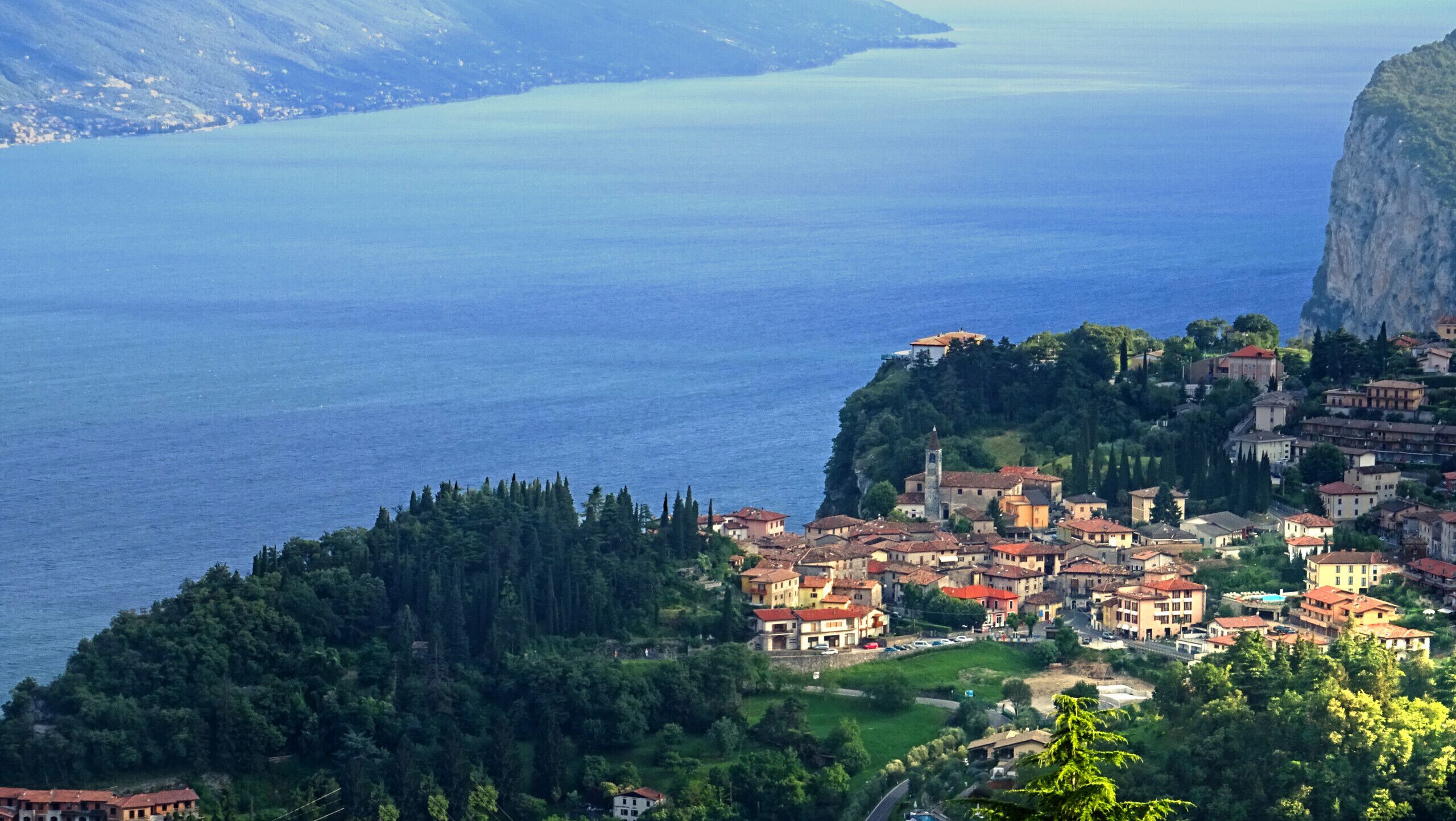 A coastal town with buildings on a hillside overlooking a large body of water.