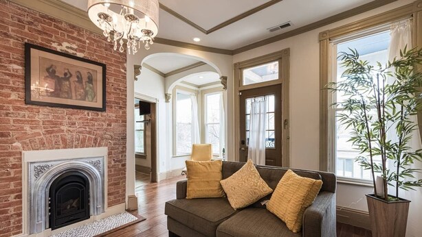 A living room with a fireplace, a sofa with cushions, a large potted plant, and a chandelier. - Elegant, King Bed, Privacy,  Free Parking (Washington)
