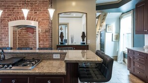 A kitchen with a brick wall, granite countertop, gas stove, and a bar stool. - Elegant, King Bed, Privacy,  Free Parking (Washington)