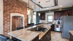A modern kitchen with a brick wall, granite countertops, dark wooden cabinets, and stainless steel appliances. - Elegant, King Bed, Privacy,  Free Parking (Washington)