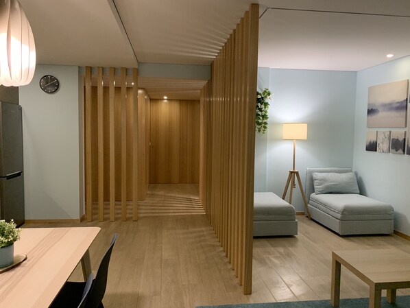 A modern room with a wooden partition, a sofa, a lamp, and a dining area. - Casa do Recife: Apartment (Viana do Castelo)