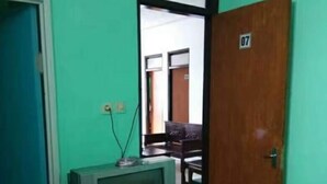 Une pièce avec un téléviseur posé sur un meuble, une porte en bois portant le numéro 07 et un sol carrelé.