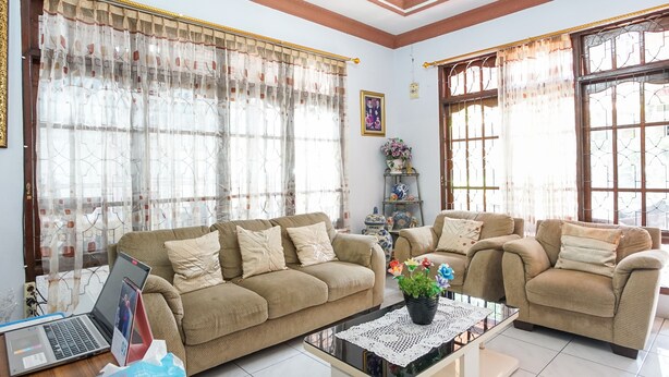 A living room with two sofas, a coffee table, and a laptop on a wooden floor. - PAS Residence (Manado)