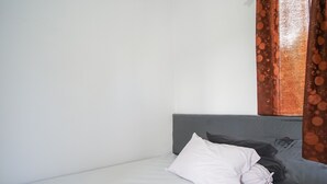 A single bed with a grey headboard and a white pillow.