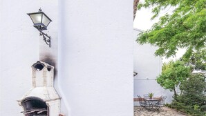 Una pared blanca con un farol decorativo y una chimenea pequeña y ornamentada.