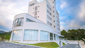 A modern hotel with a curved facade, large windows, and a flat roof. - Tri Hotel São João Batista (Sao Joao Batista)