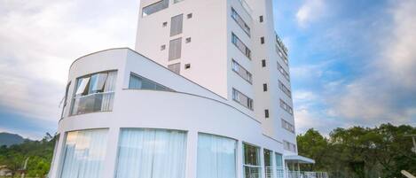 A modern hotel with a curved facade, large windows, and a flat roof.