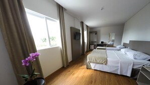 A hotel room with two beds, a desk, a chair, a TV, and a window with curtains. - Tri Hotel São João Batista (Sao Joao Batista)