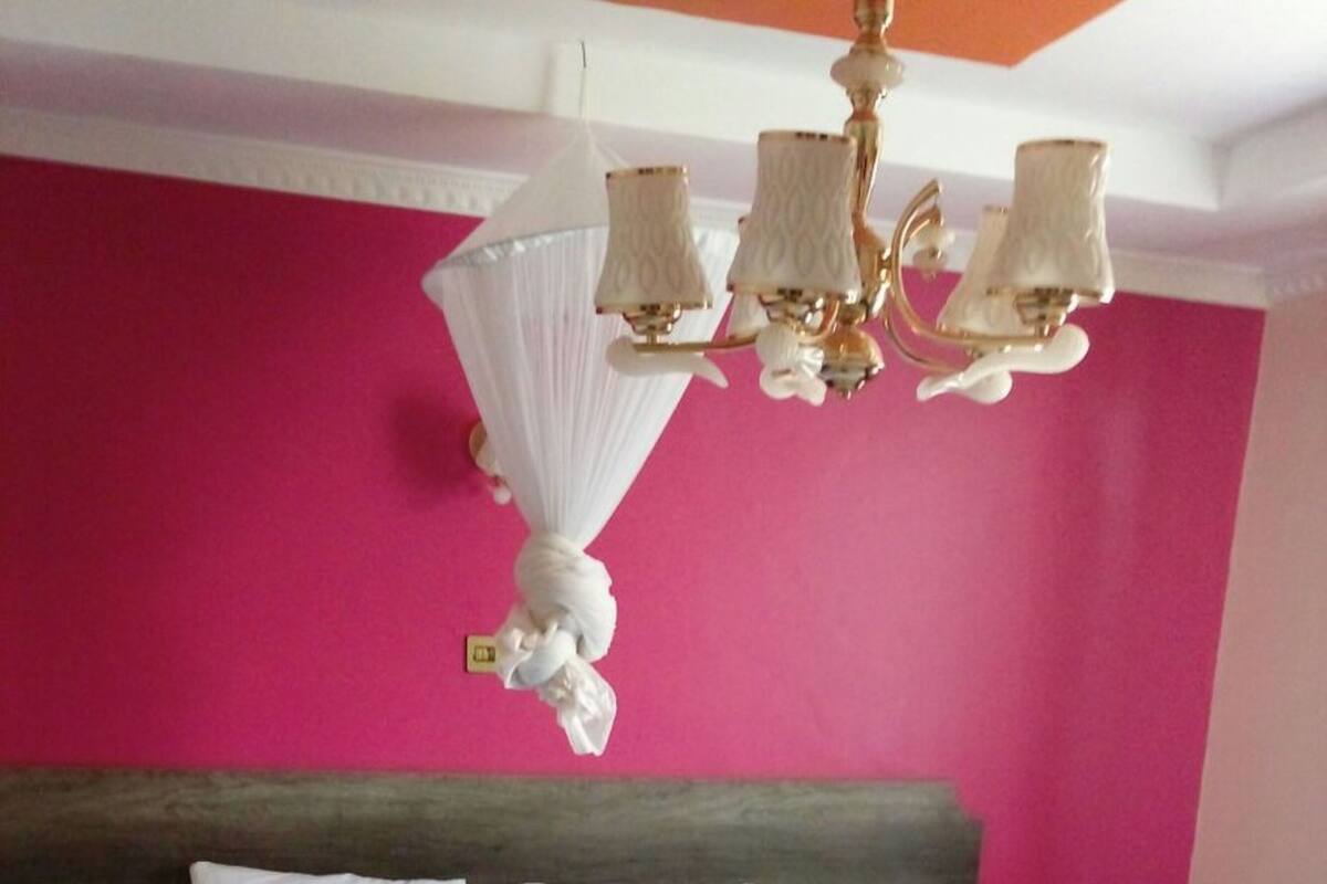 A bedroom with a bed, a nightstand, a bedside table, a lamp, and a wall-mounted light fixture.
