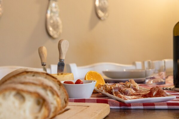 Desayuno con pan, tomates, una naranja y tocino sobre un mantel a cuadros.
