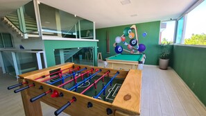 A room with a foosball table, a pool table, and a staircase leading to an upper level. - Porto Sol Flats by AFT (Ipojuca)
