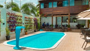 Una piscina con borde azul, rodeada de plantas en macetas y mobiliario de exterior.